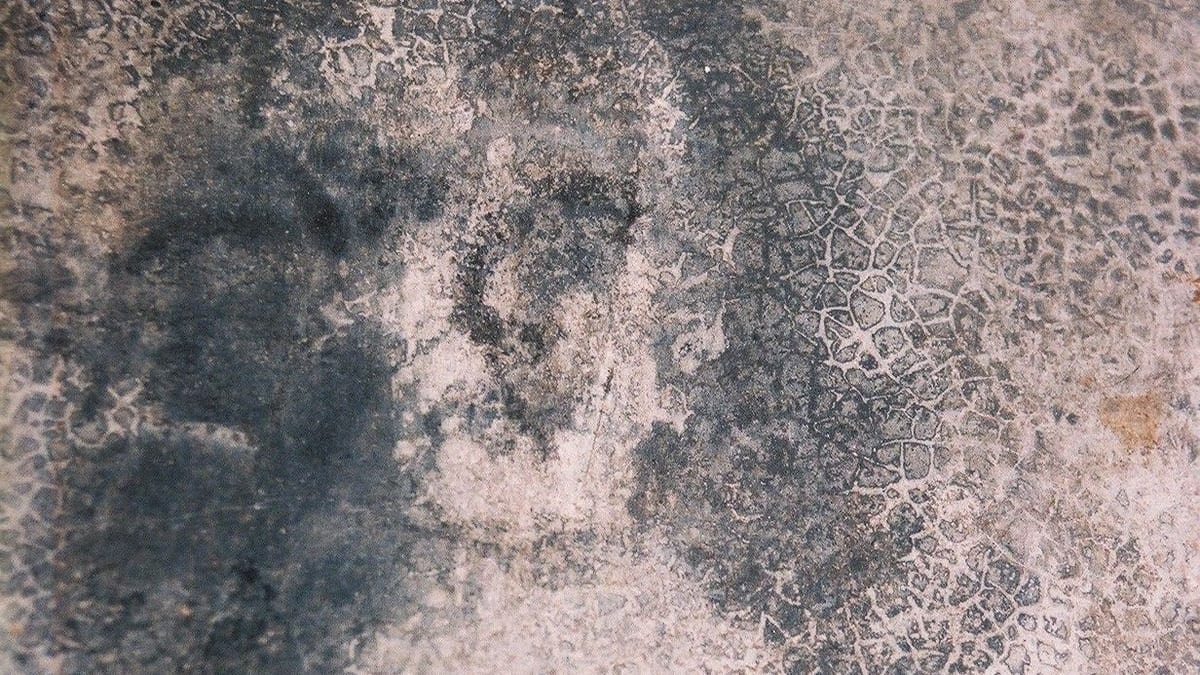 Rostro borroso de mujer formado por manchas en el suelo de cemento de la casa de Bélmez, fotografiado en 1992