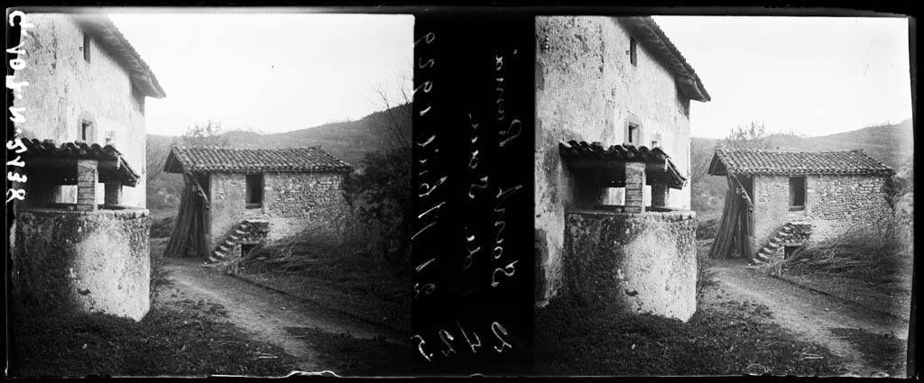 Fotografía doble en blanco y negro de una calle de Sant Romà de Sau con un pozo de piedra y una casa con escalera